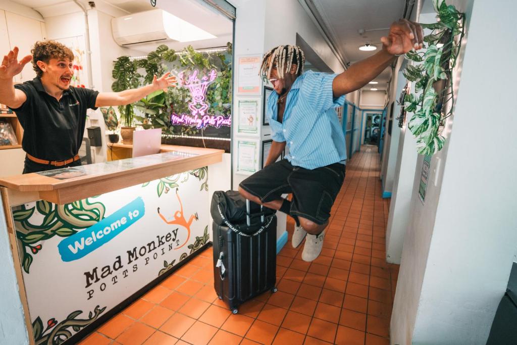 a man sitting on a suitcase in front of a counter at Mad Monkey Potts Point in Sydney