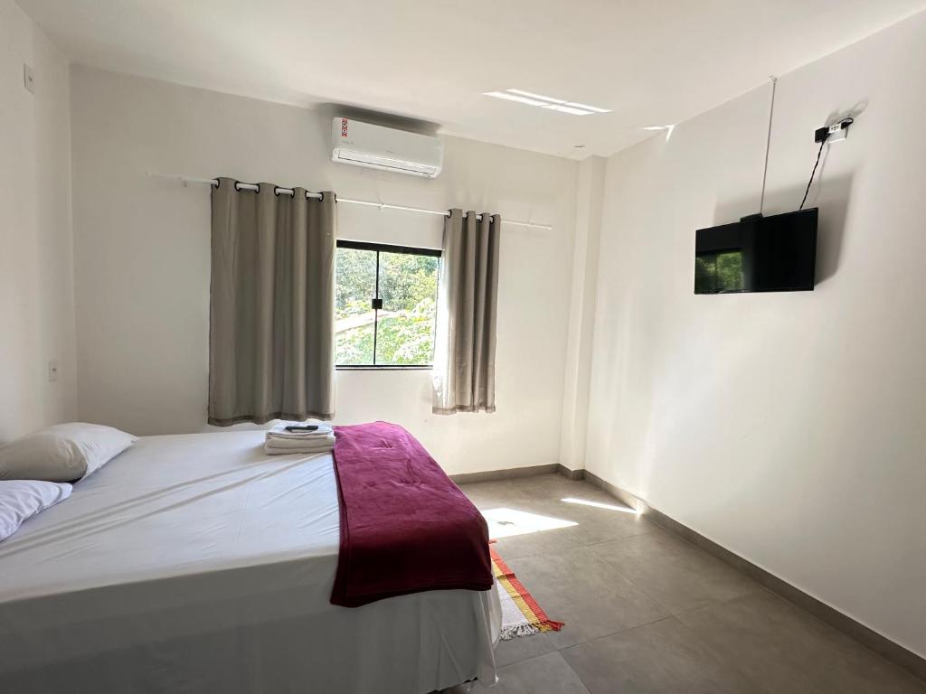 a bedroom with a large bed and a window at Pousada caminho das águas in Pirenópolis