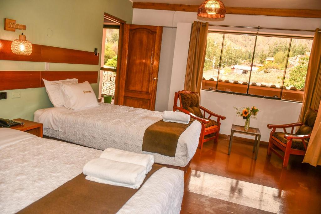 a hotel room with two beds and a window at Hotel Boutique MIRANDO AL SOL in Ollantaytambo