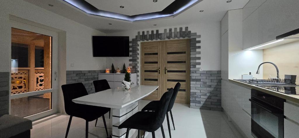een keuken met een witte tafel en zwarte stoelen bij Apartament u Krupy in Murzasichle