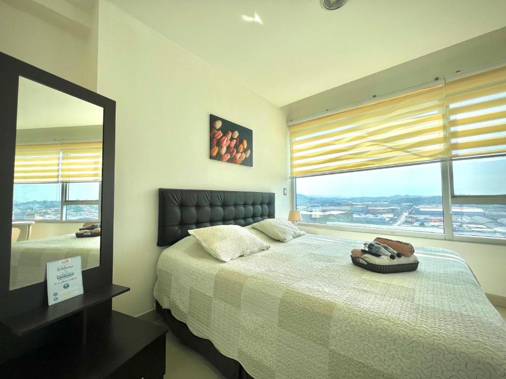 a bedroom with a bed with a mirror and a window at Luxury City Suites in Guayaquil