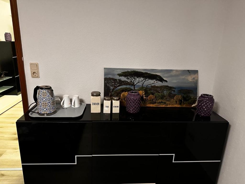 a black dresser with vases and a painting on it at Dortmund Brackel Wohnung in Dortmund