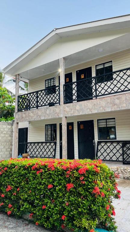 a building with black doors and red flowers in front at Posada Kotnat in San Andrés