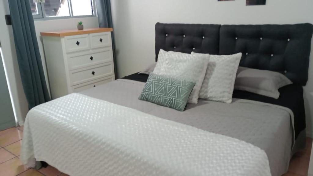 een bed met een zwart hoofdbord en een witte commode bij Hotel Gayra in Antofagasta