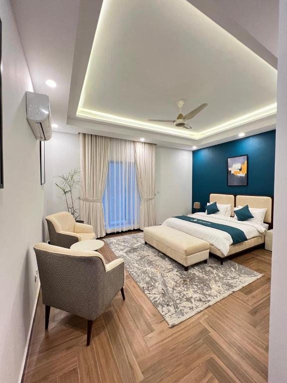 a bedroom with a bed and a couch and chairs at Capital Family Lodges Islamabad in Islamabad