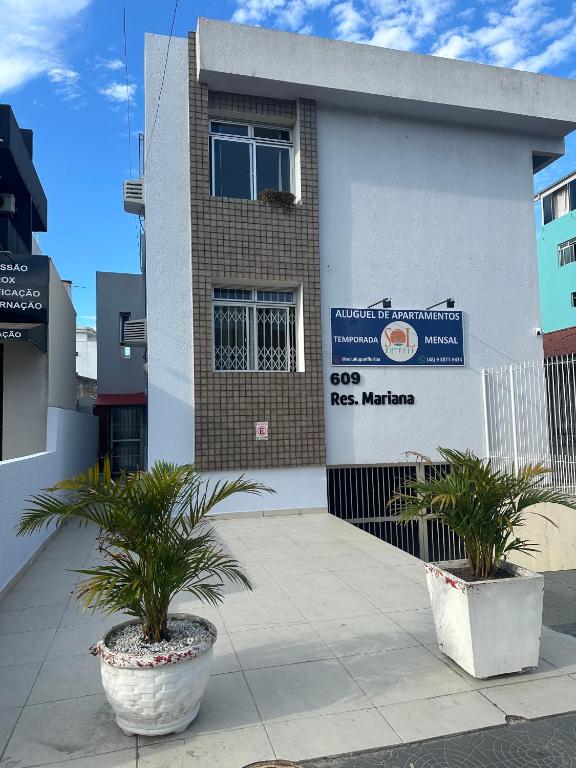 a building with two potted plants in front of it at Sol-datelli Apês Floripa in Florianópolis