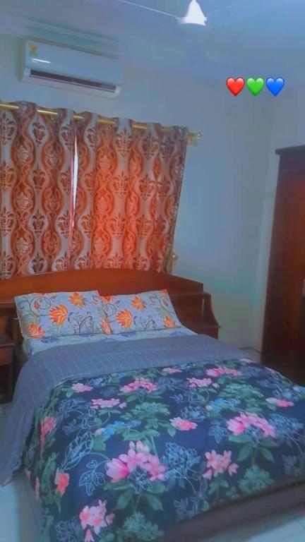 un lit avec une couette bleue avec des fleurs dessus dans l'établissement Beach Road, à Sékondi