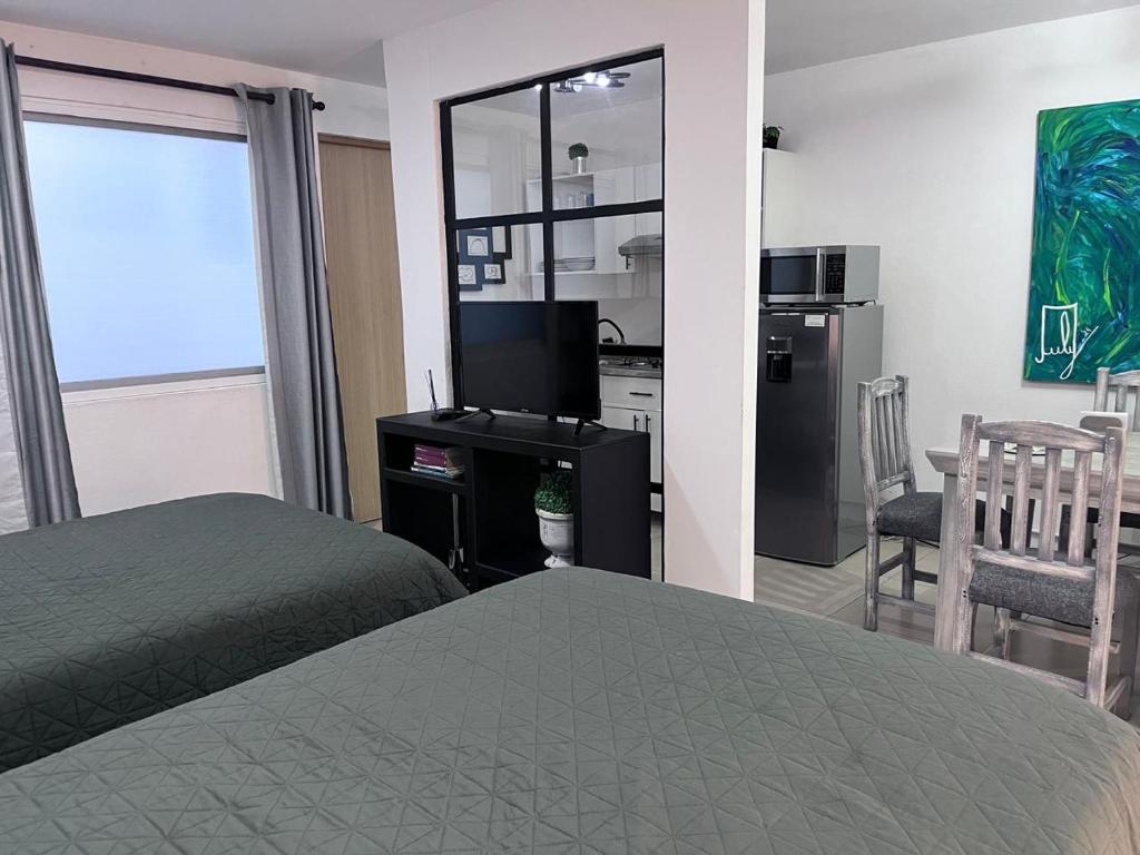 ein Schlafzimmer mit einem Bett und einem TV sowie eine Küche in der Unterkunft Lindo y comodo Loft in Hércules