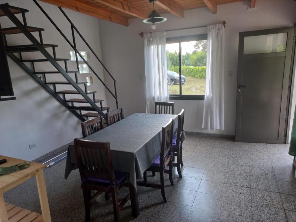 una sala da pranzo con tavolo, sedie e scala di Lo de la Abu a Villa Las Rosas