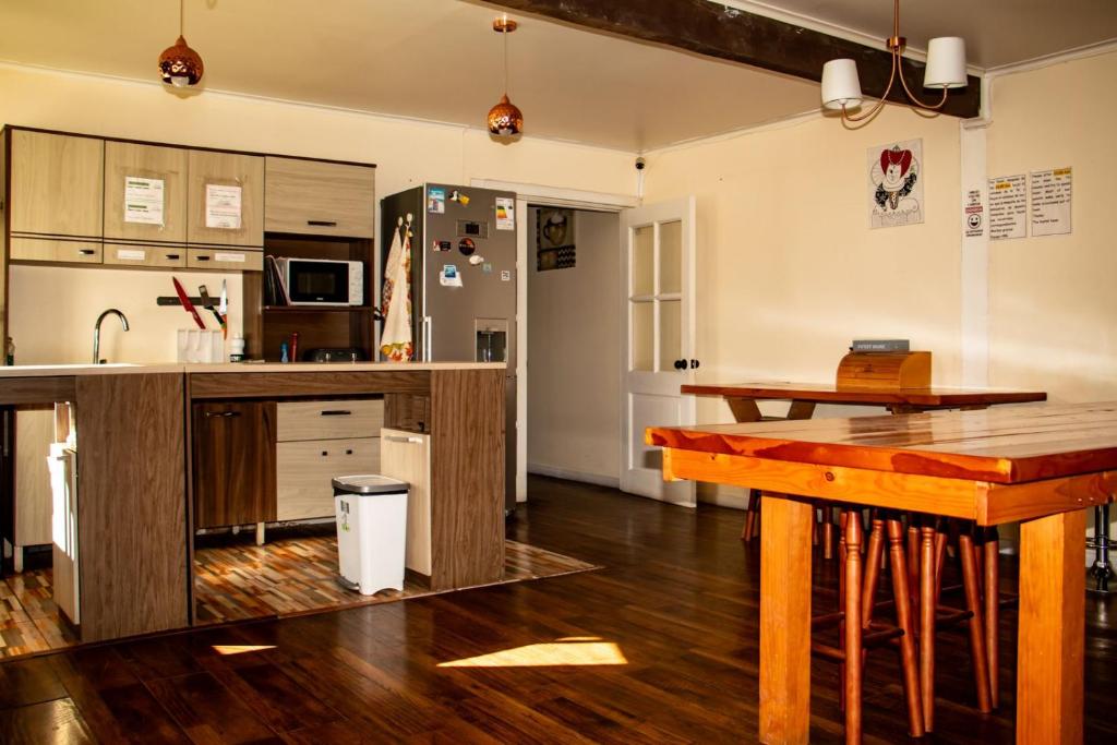 a kitchen with wooden tables and a refrigerator at Hostal Turpial Patagonia in Puerto Natales