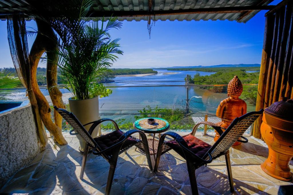 een vrouw zit op een terras met uitzicht op een rivier bij Vila Paisagem in Barra de Guaratiba