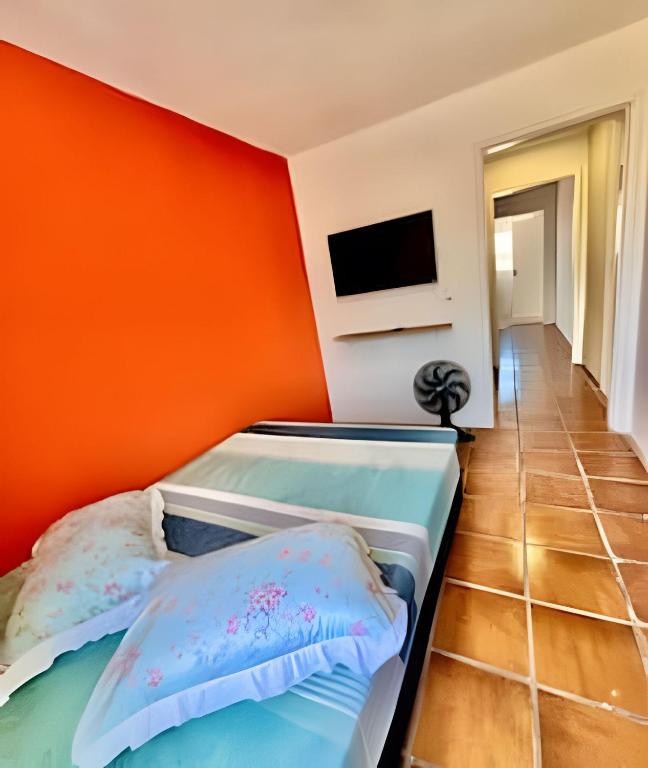 a bedroom with an orange wall and a bed at BriSa Do Mar < Flecta Matinhos in Matinhos