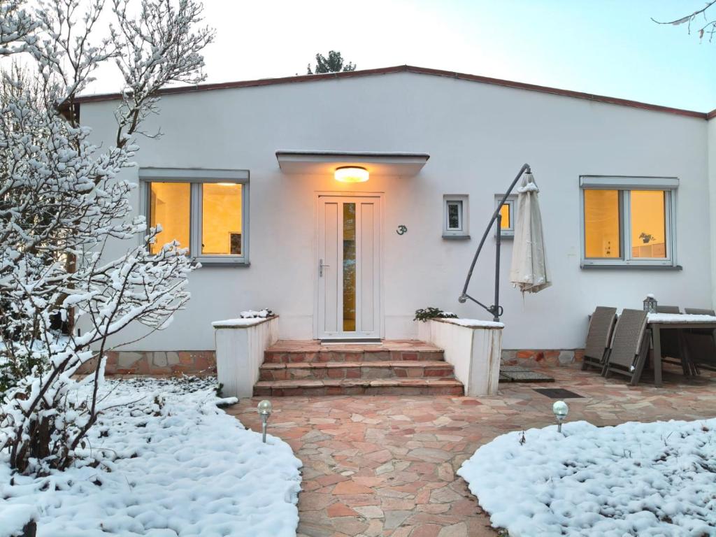 ein weißes Haus mit gelber Tür im Schnee in der Unterkunft Gemütliches Haus mit Schwedenofen im Wienerwald in Neulengbach
