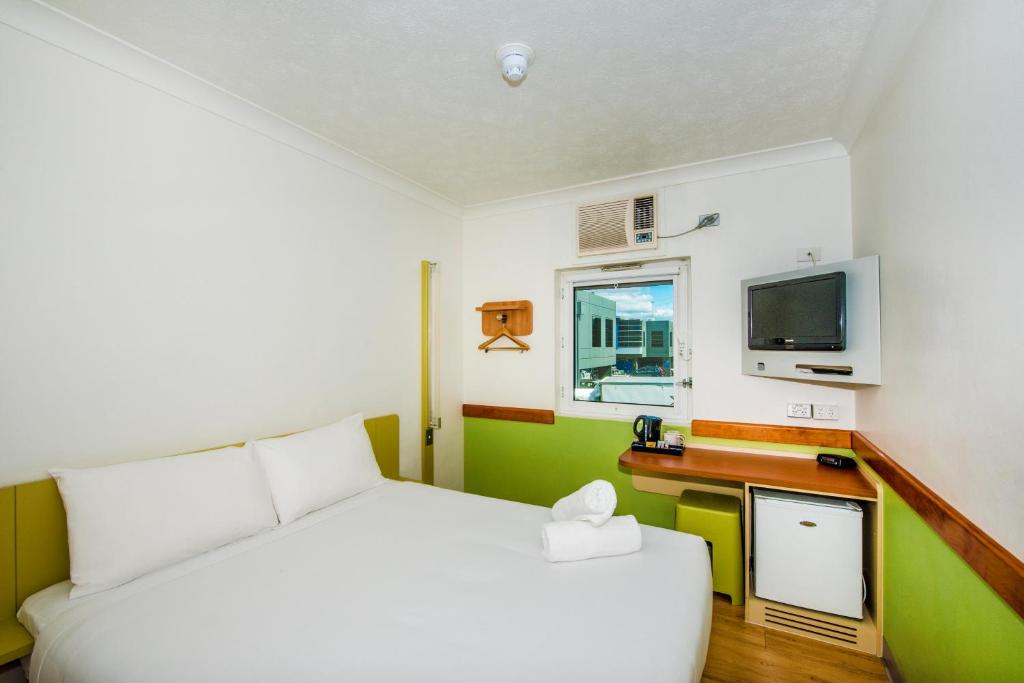a bedroom with a white bed and a television at ibis Budget Brisbane Airport in Brisbane