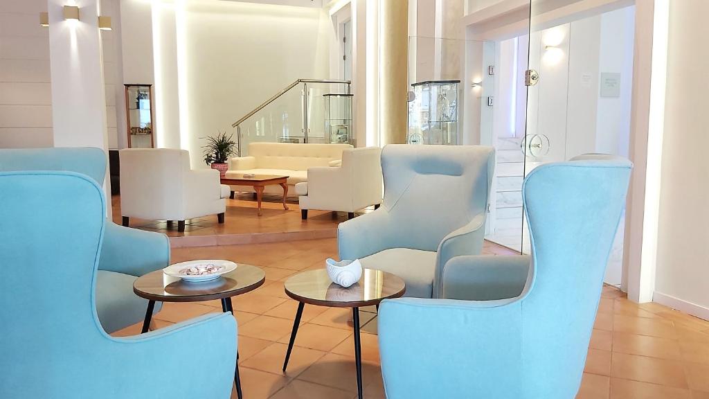 a living room with blue chairs and a table at Akrogiali Exclusive Hotel (Adults Only) in Polychrono