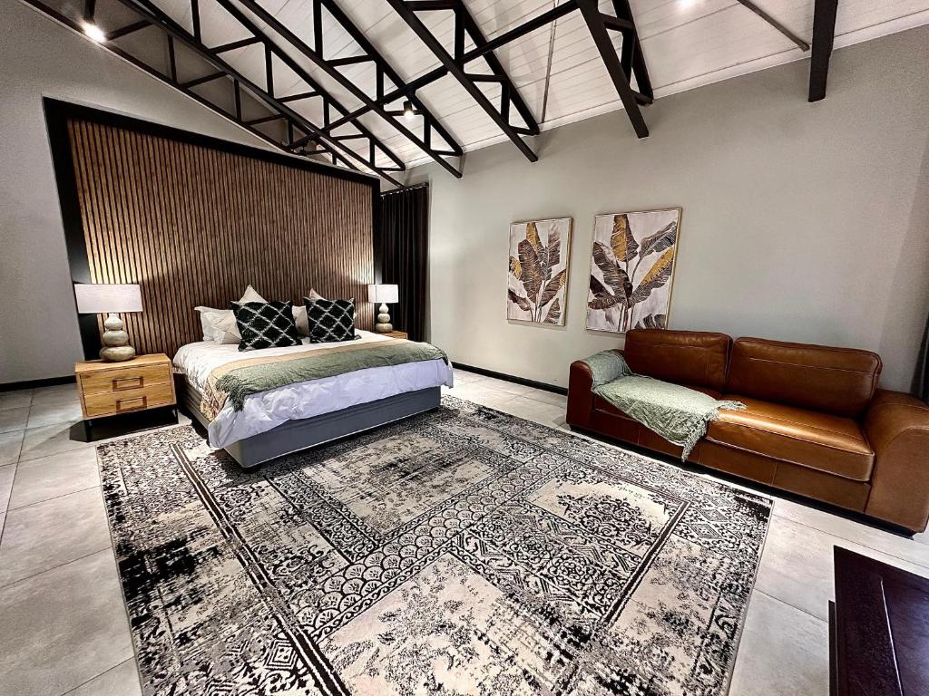 a bedroom with a bed and a couch and a rug at Fairview Guest House Executive in Hartswater