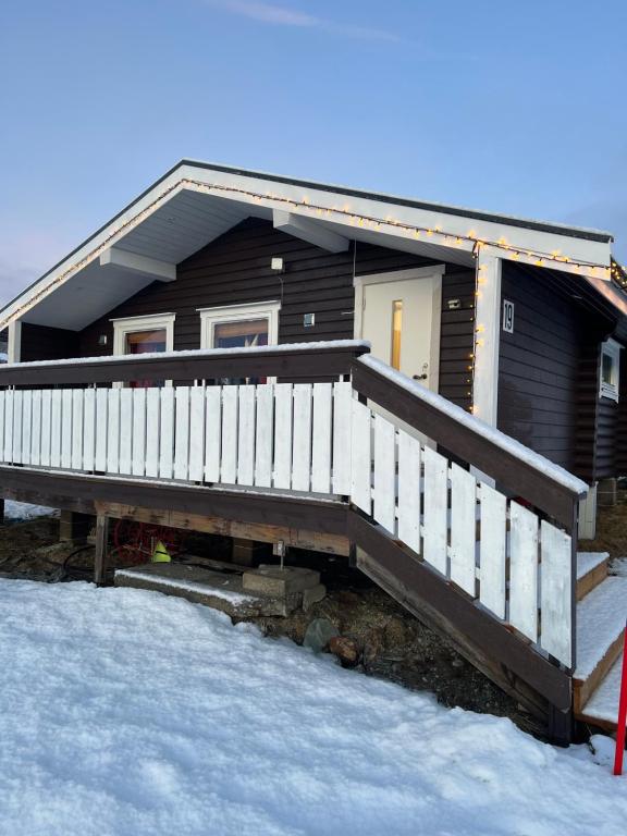 a house with a wooden deck in the snow at Øse Camping in Gratangen