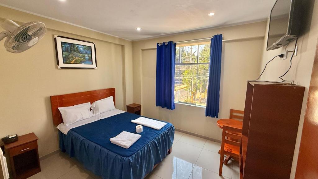 ein Schlafzimmer mit einem Bett mit blauen Laken und einem Fenster in der Unterkunft Ikasur Hotel in Ica