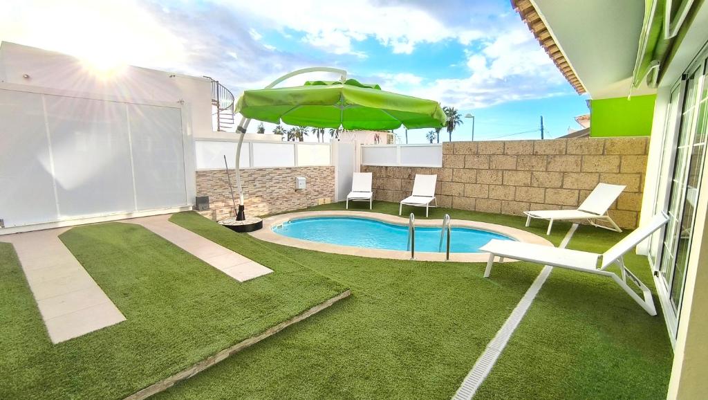 a backyard with a swimming pool and an umbrella at HEI HEI AND PUA VILLA - heated pool, priv parking, fibre net, Palm-Mar in Palm-Mar