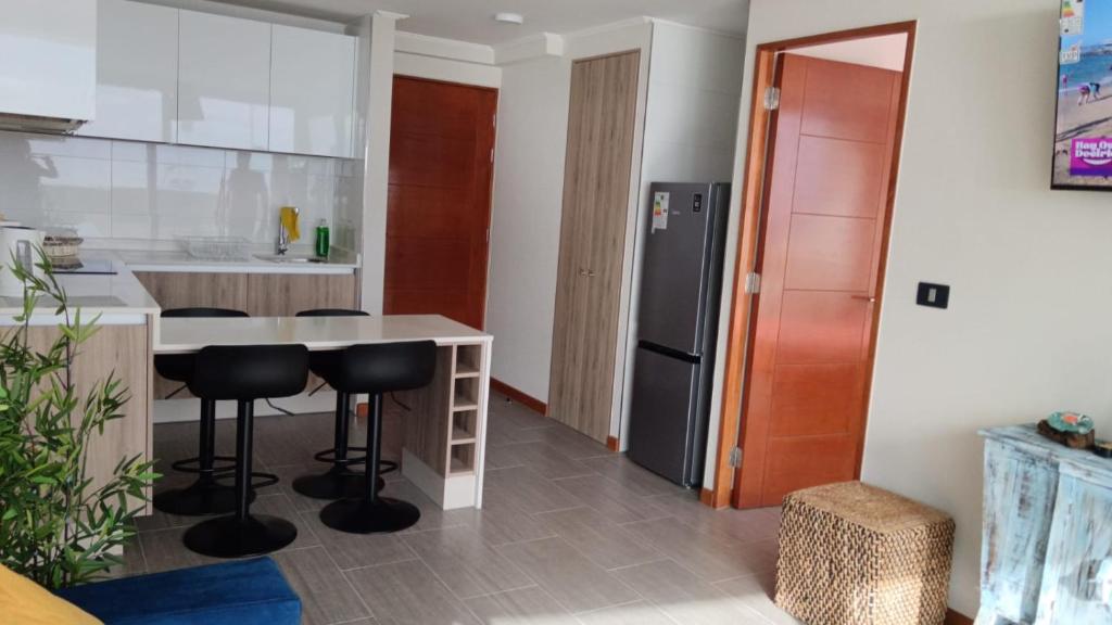 een keuken met een aanrecht en twee barkrukken bij Departamentos en Edificio Distrito Cavancha 1 in El Cerrillo