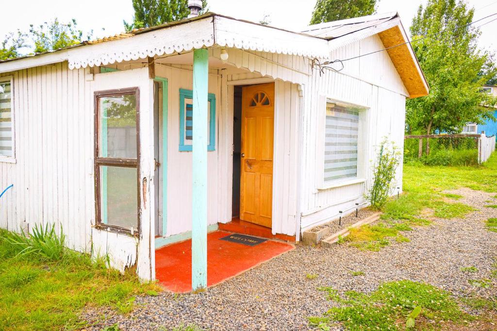 un piccolo capanno bianco con una porta e un portico di Cabañas del Río Bueno a Río Bueno