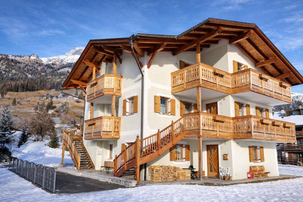 a large building with wooden balconies on the side in the snow at Cèsa Nicole e Patrick in Campitello di Fassa