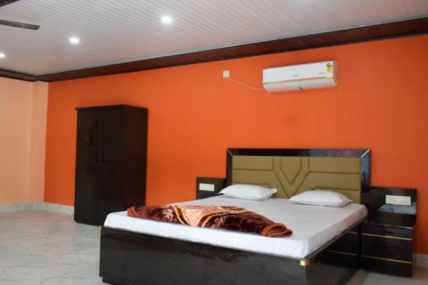 a bed in a room with an orange wall at Pine Apple Resorts in Jalpāiguri