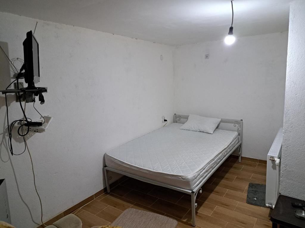 een kleine slaapkamer met een bed en een televisie bij Hostel Lalinac in Lalince