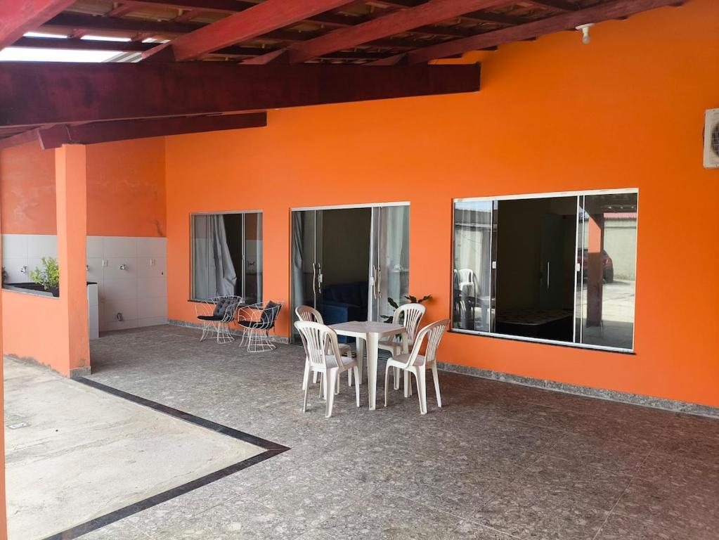 een patio met een tafel en stoelen in een oranje muur bij Casa da Hellen in Porto Seguro