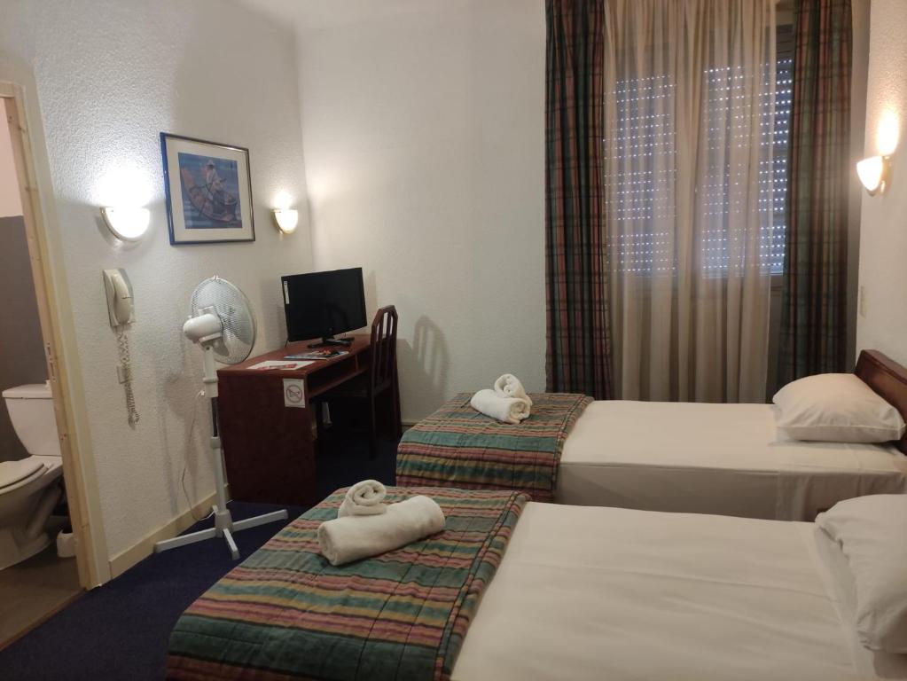 a hotel room with two beds and a desk at Hôtel de Nevers in Lourdes
