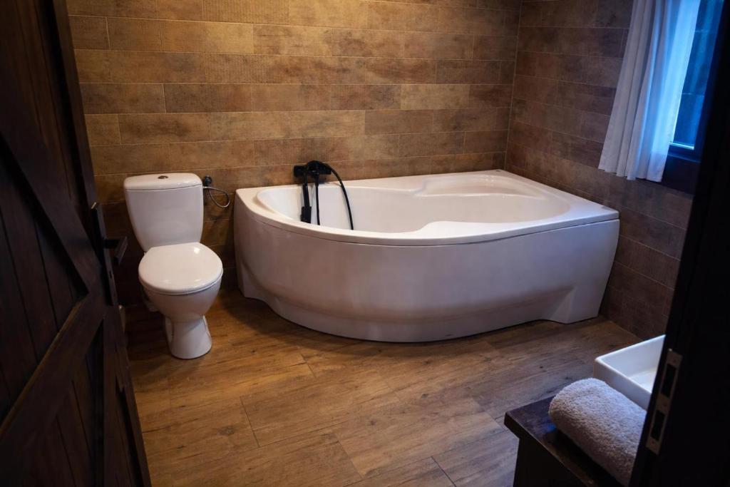 une salle de bain avec une baignoire blanche et des toilettes dans l'établissement Osada Brzeziny - 25 minut od Warszawy - sauna, balia z jacuzzi, basen, altana, grill, ogród, ognisko, à Brzeziny