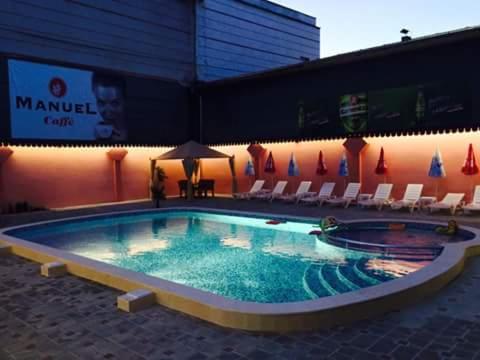 una gran piscina con sillas y un edificio en Family Hotel Relax en Strelcha