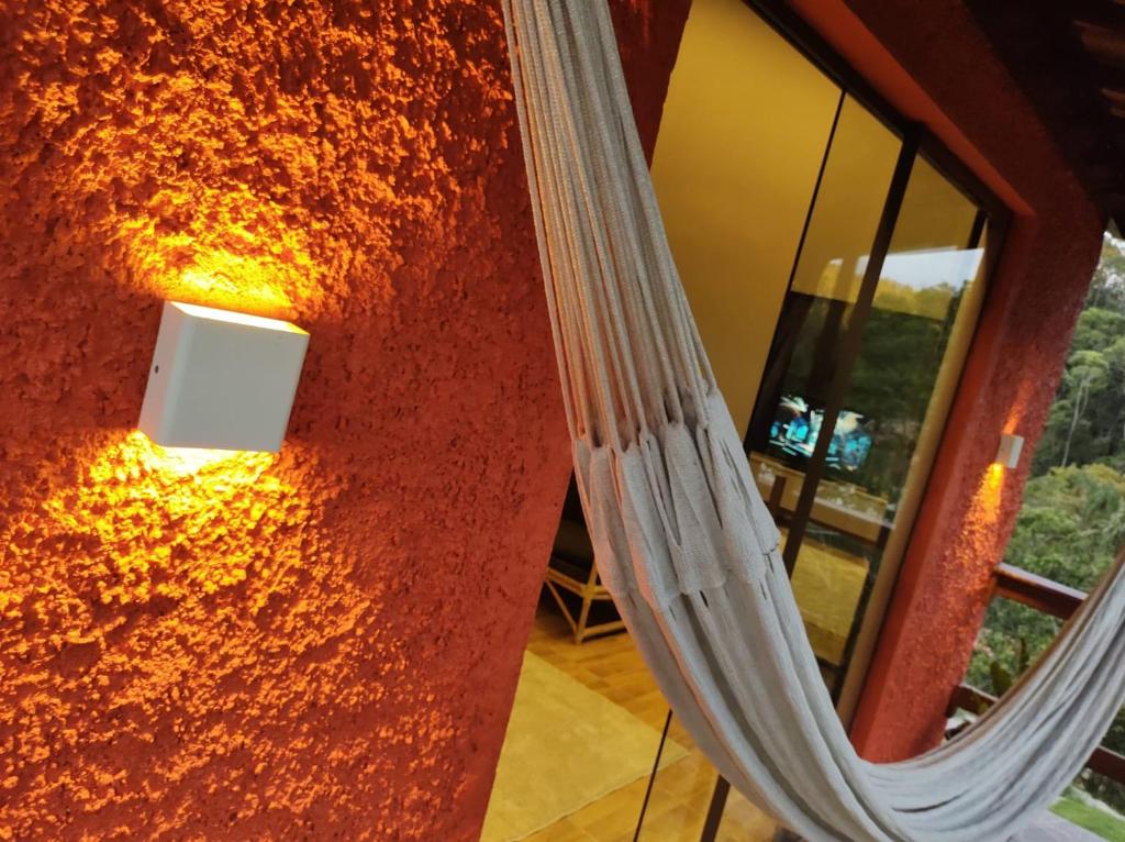 een spiegel aan een muur met een licht erop bij Chalé Freital in Nazaré Paulista