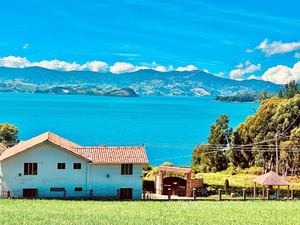 ein weißes Haus mit Blick auf das Wasser in der Unterkunft Cabaña Valle De La Laguna, jacuzzi y vista al Lago in Aquitania