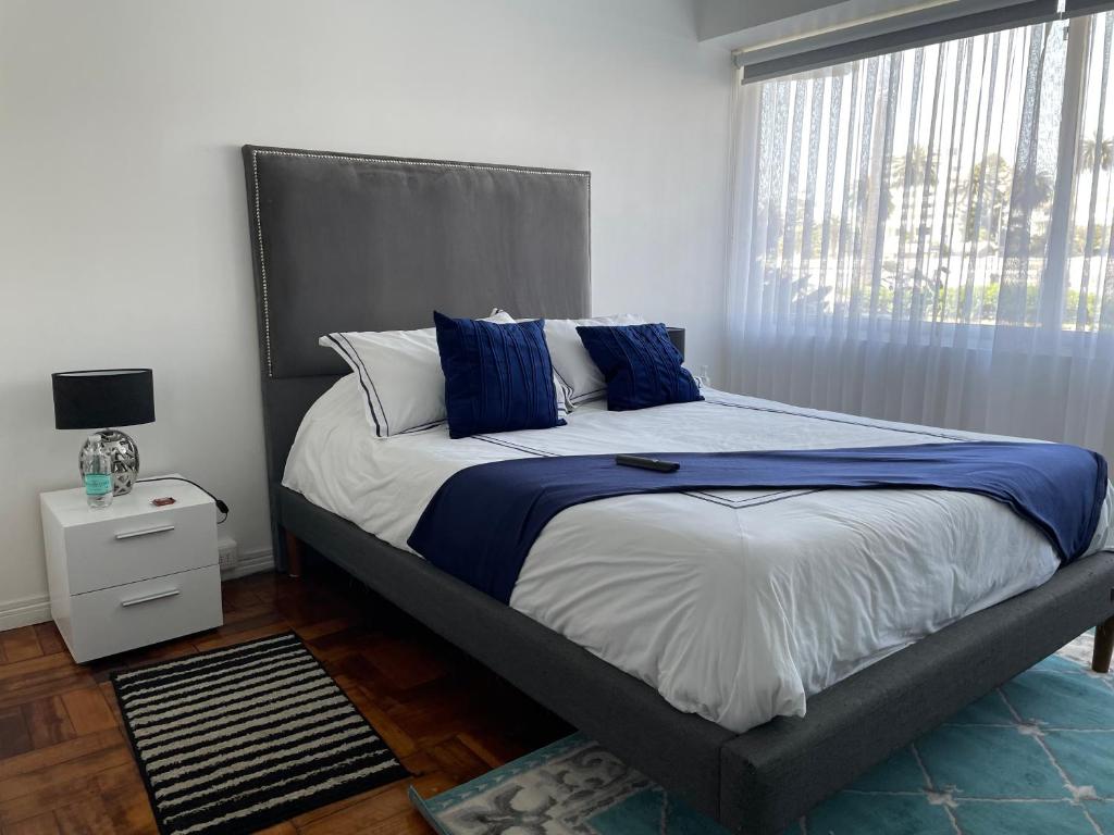een slaapkamer met een bed met blauwe kussens en een raam bij Lechón Marina in Viña del Mar