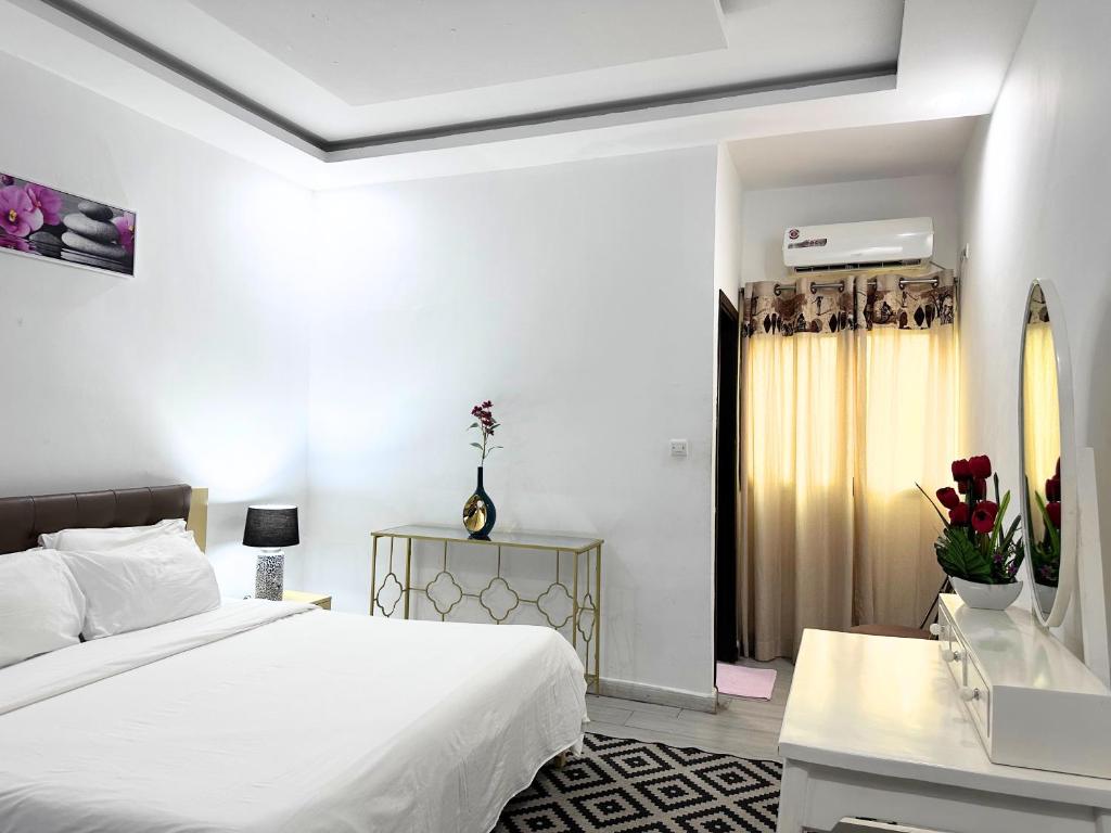 biała sypialnia z łóżkiem, biurkiem i oknem w obiekcie Residences Riverside Abidjan w mieście Abidżan