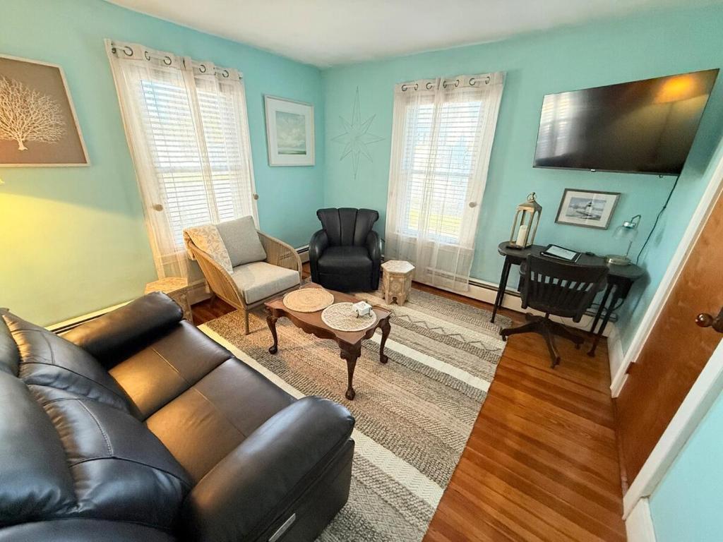 a living room with a leather couch and a table at Gallows Hill Guest House in Salem