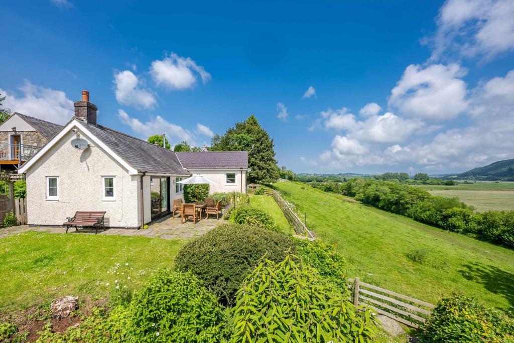 a white house on a hill with a yard at Llwyn-Y-Coed-Isaf in Llanbedr-y-cennin