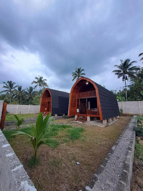 a brown and black building with palm trees in the background at Rinjani Koceng Bungalows in Tetebatu