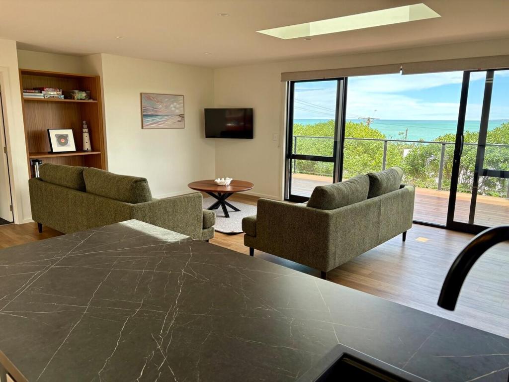 a living room with two couches and a view of the ocean at 45 degrees South in Kakanui