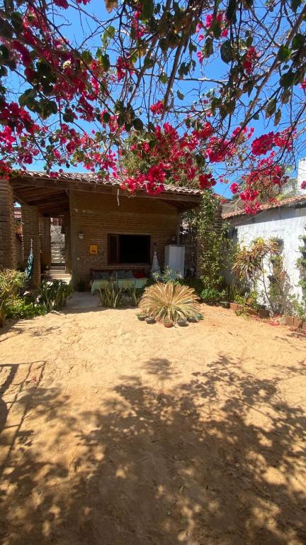 een huis met rode bloemen aan de voorkant bij Casa Bari in Jericoacoara