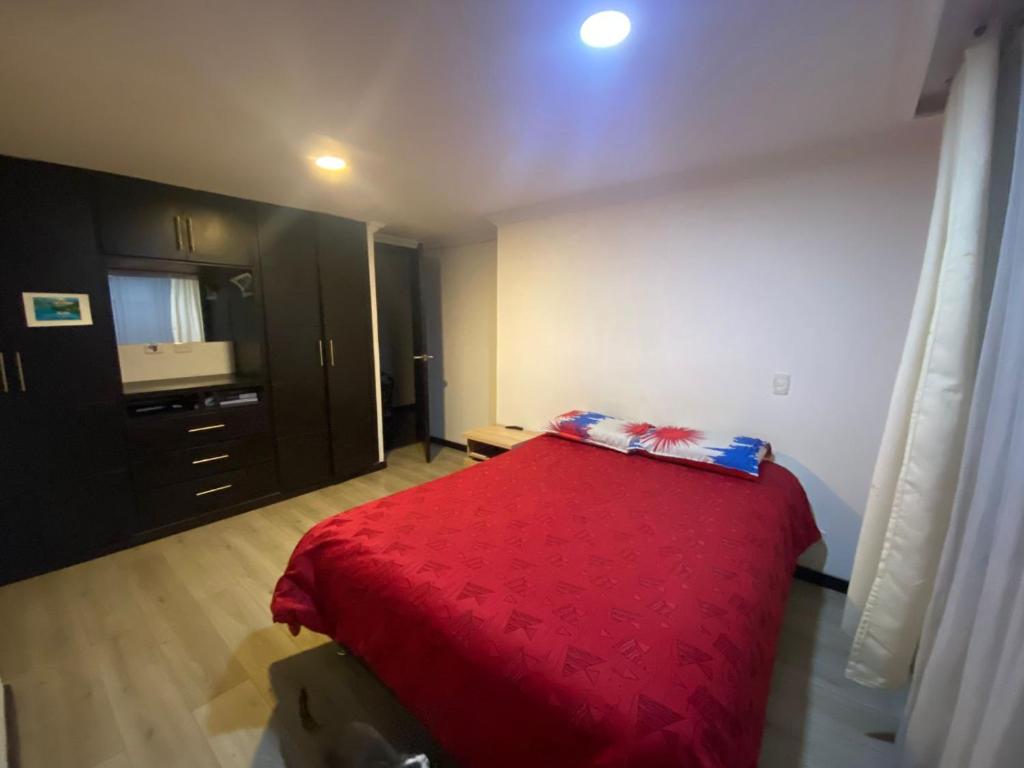 una camera con letto rosso e armadio nero di Estancia Morasurco a Estación El Salto