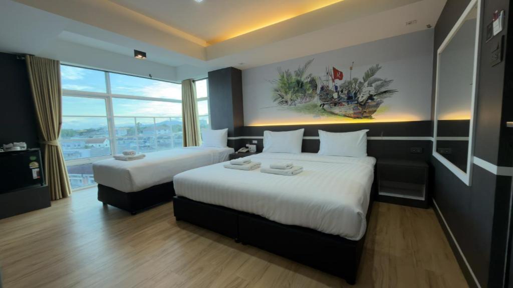 una camera d'albergo con due letti e una grande finestra di โรงแรมริเวอร์ ซิตี้ ปัตตานี a Ban Ru Sa Mi Lae