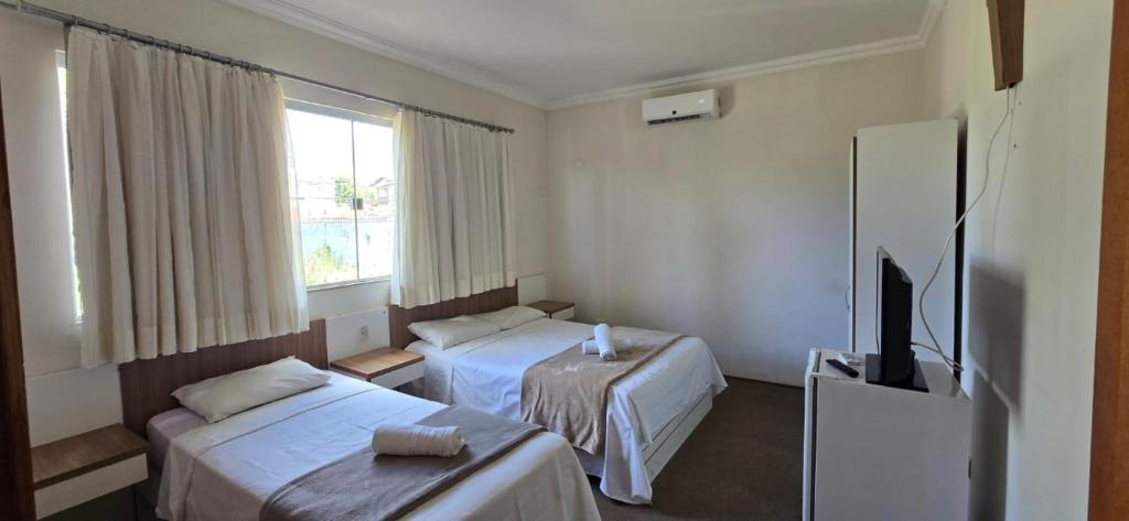 a room with two beds and a flat screen tv at Hotel Norte Sul in Campo Grande