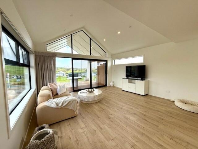 ein großes Wohnzimmer mit einem Sofa und einem TV in der Unterkunft Light-Filled Coastal Hideaway in Raglan