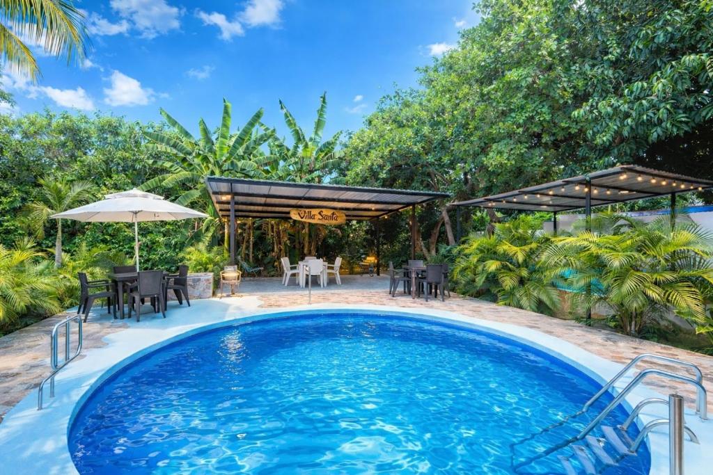 an outdoor pool with a table and chairs and an umbrella at Villa Tranquila - Paraíso Privado con Piscina y Amplios Espacios Naturales con Casa Campestre in Ricaurte