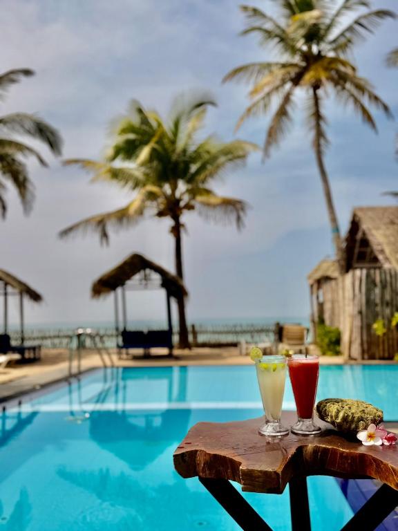 two drinks on a table next to a swimming pool at Luvora Villa in Ambalangoda