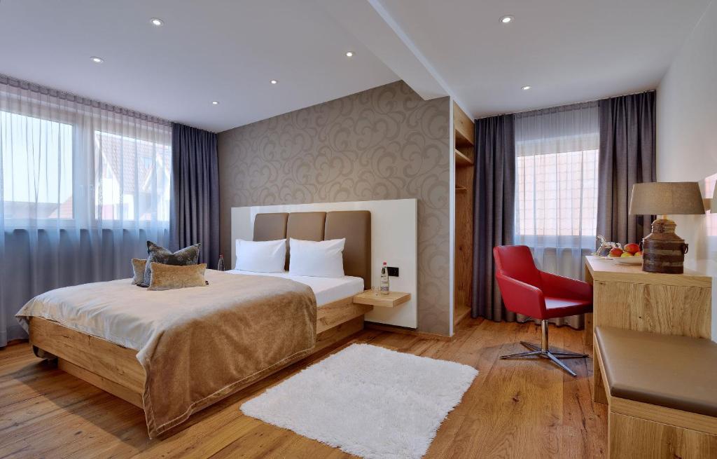 a hotel room with a bed and a red chair at Landhotel RÖSSLE in Stimpfach