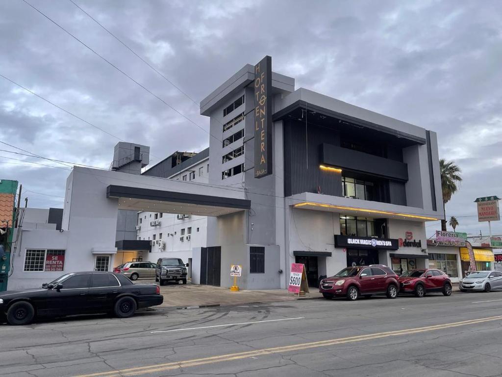 a building with cars parked in front of it at Hotel Frontera Baja in Mexicali