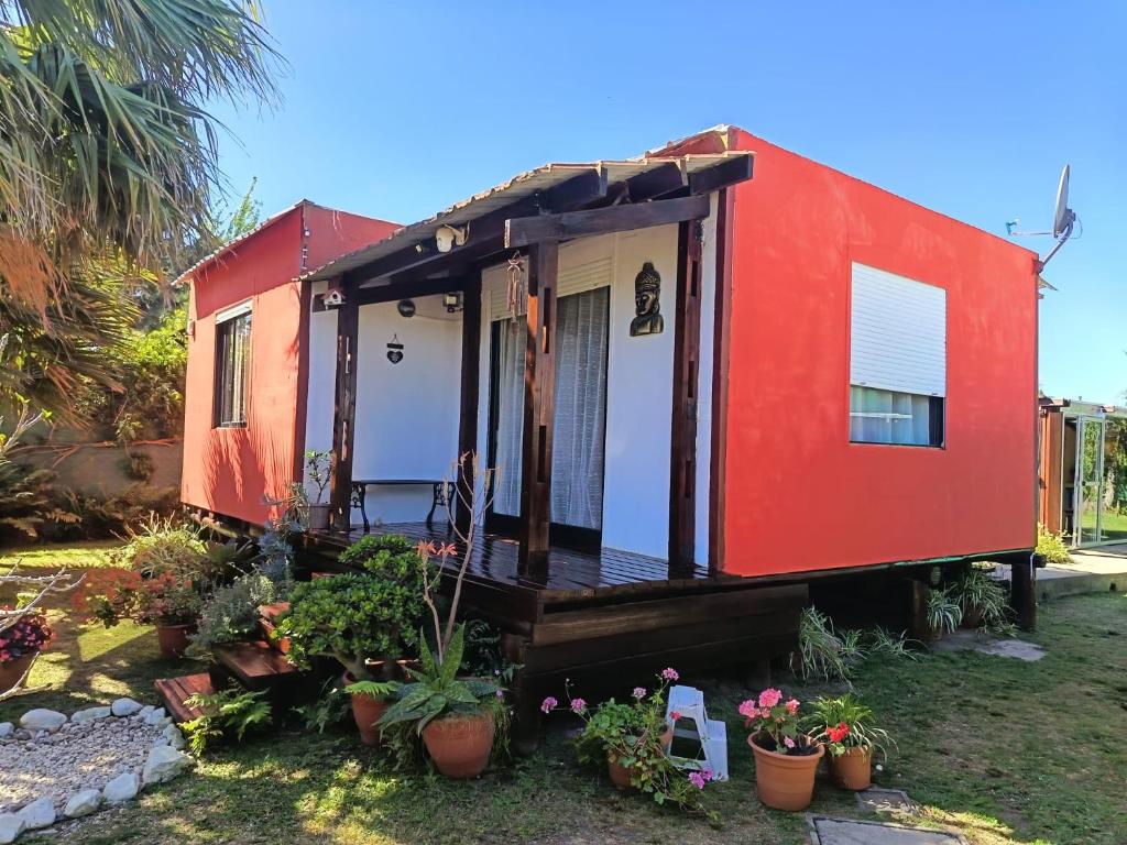 a red tiny house in a yard with potted plants at Eternal Sun in Balneario Buenos Aires
